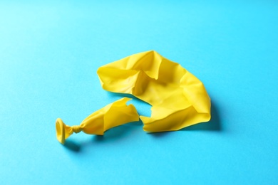 Photo of Popped yellow latex balloon on color background