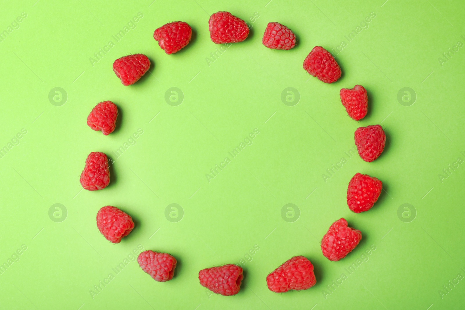 Photo of Frame made with delicious ripe raspberries on green background. Space for text