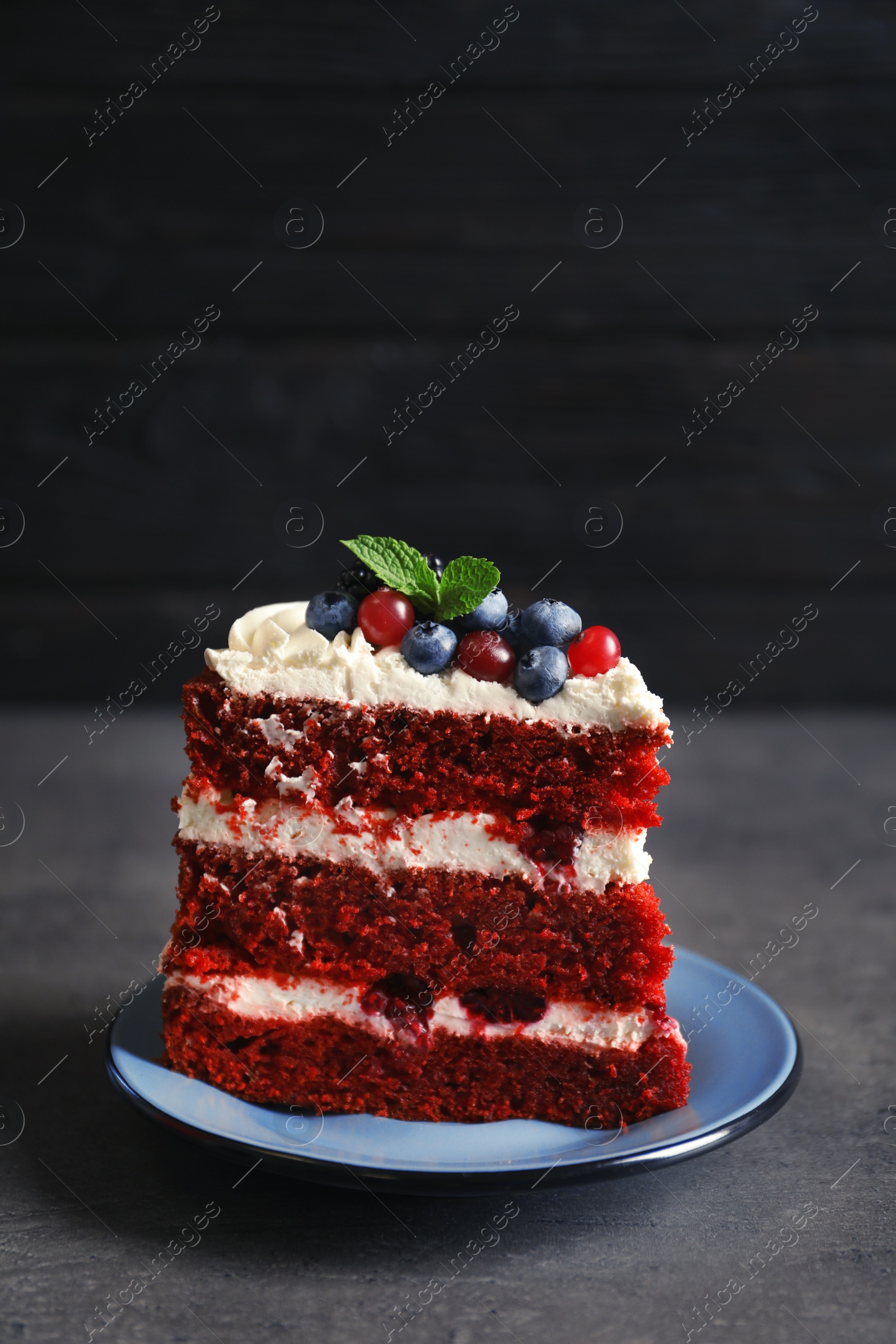 Photo of Plate with piece of delicious homemade red velvet cake on table