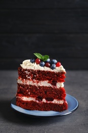 Photo of Plate with piece of delicious homemade red velvet cake on table