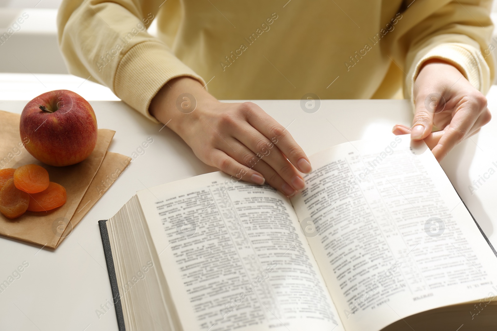 Photo of Woman with Holy Bible at white table indoors, closeup. Great Lent season