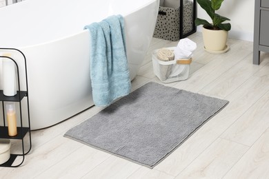 Photo of Soft light grey mat near tub in bathroom