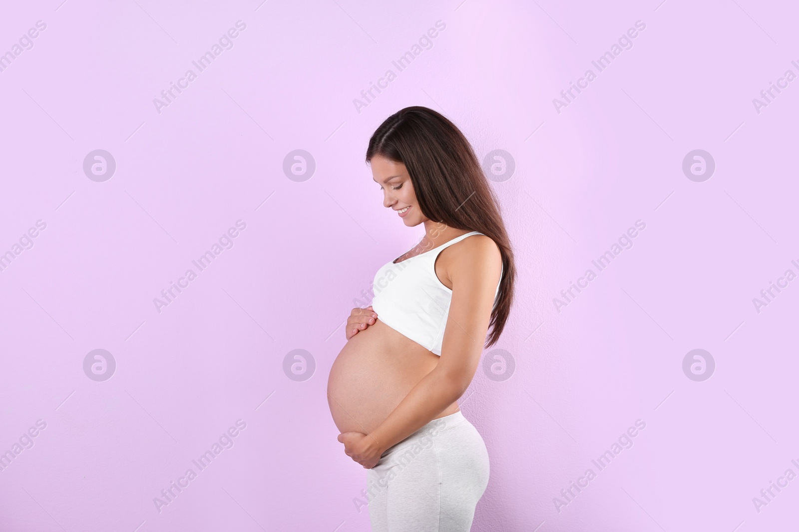 Photo of Happy pregnant woman posing on color background