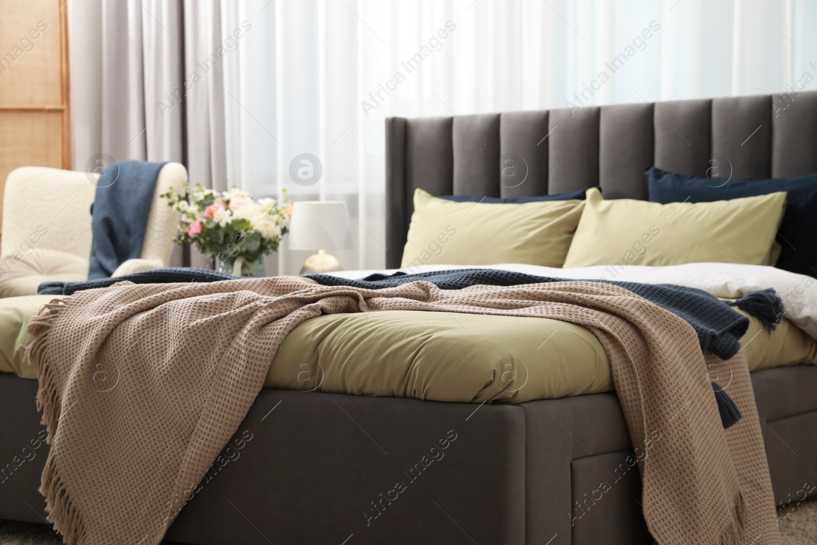 Photo of Comfortable bed with cushions and bedding in room. Stylish interior