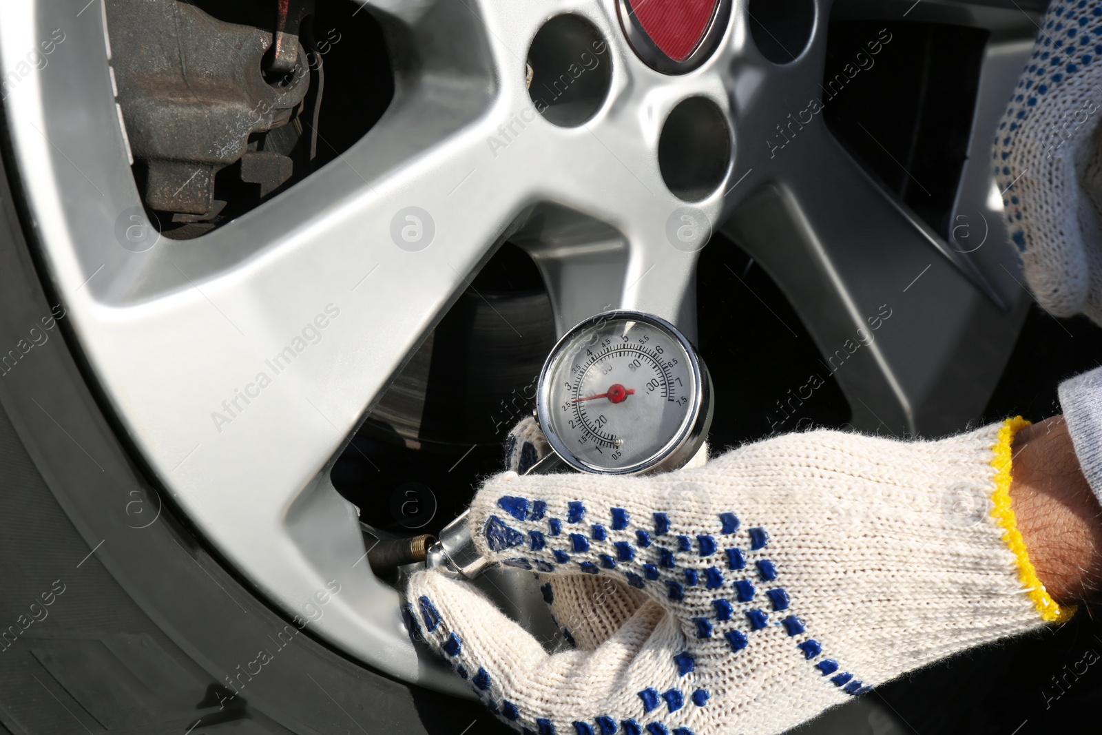 Photo of Mechanic checking tire air pressure at car service, closeup