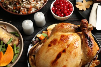 Traditional Thanksgiving day feast with delicious cooked turkey and other seasonal dishes served on black wooden table, closeup