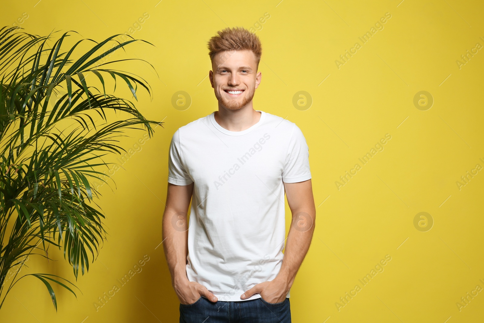 Photo of Young man wearing blank t-shirt on yellow background. Mockup for design