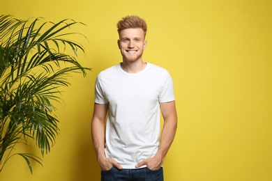 Young man wearing blank t-shirt on yellow background. Mockup for design