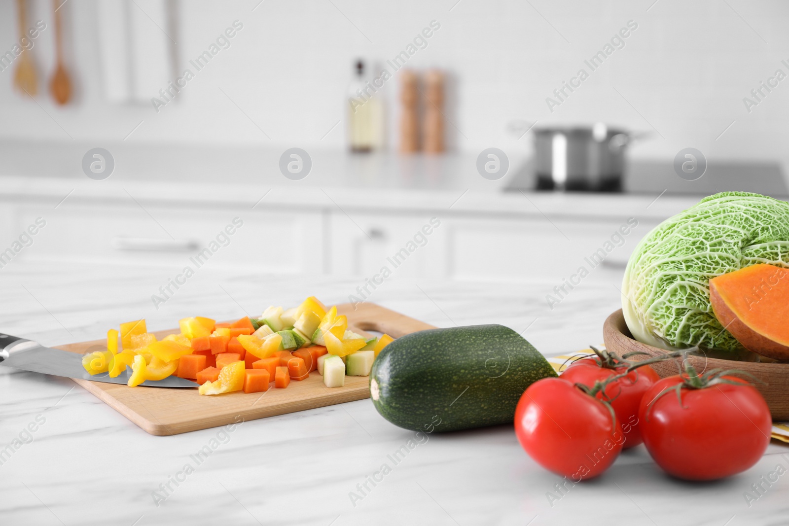 Photo of Different raw vegetables on white marble table in kitchen
