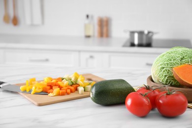 Photo of Different raw vegetables on white marble table in kitchen