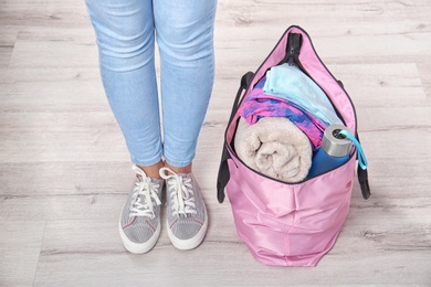 Photo of Young woman and sports bag with gym equipment, closeup. Ready for sport training