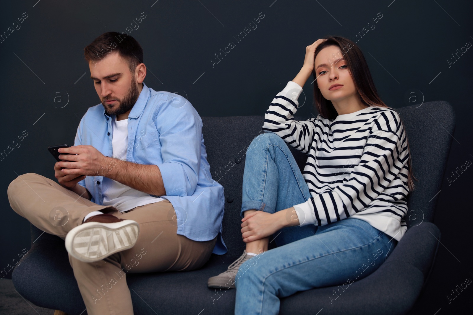 Photo of Young man preferring smartphone over his girlfriend at home. Relationship problems