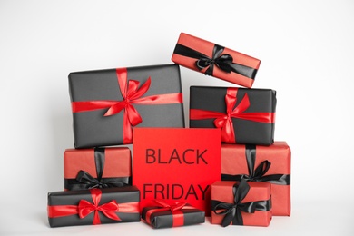 Many gift boxes and sheet of paper with words Black Friday on white background