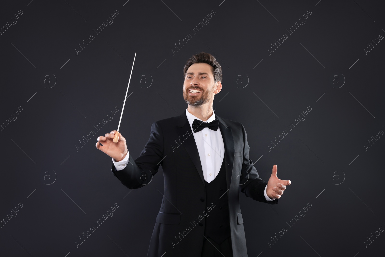 Photo of Happy professional conductor with baton on black background