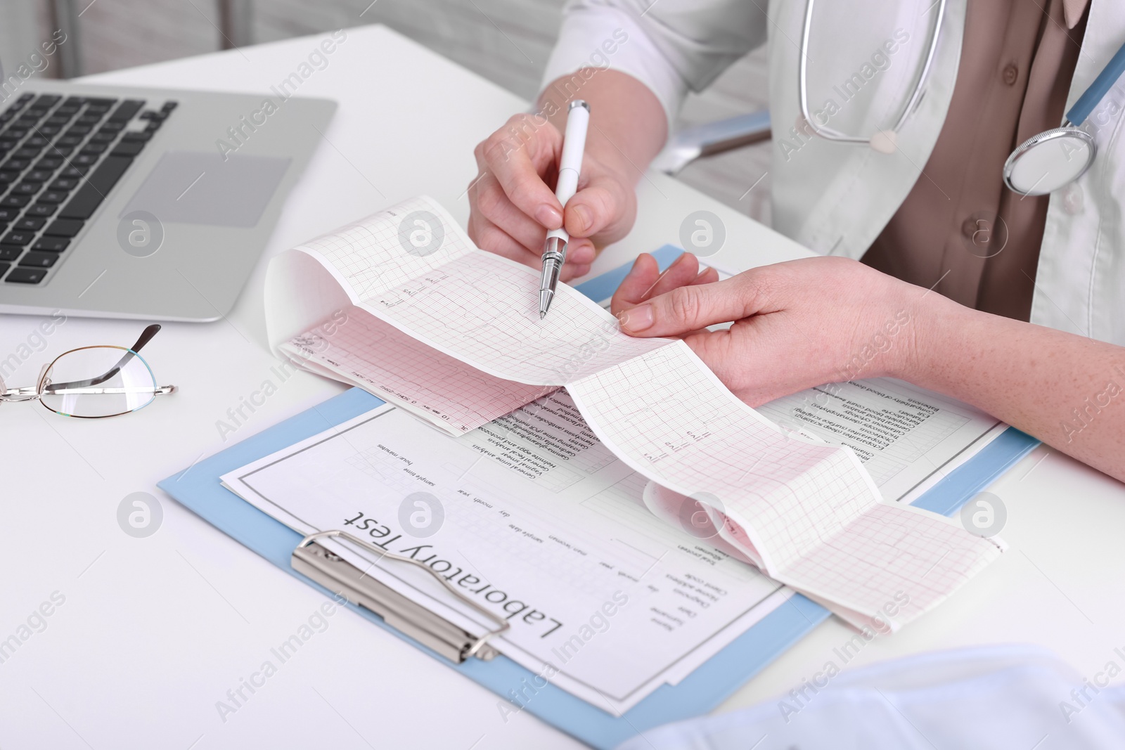 Photo of Doctor examining cardiogram at table in clinic, closeup