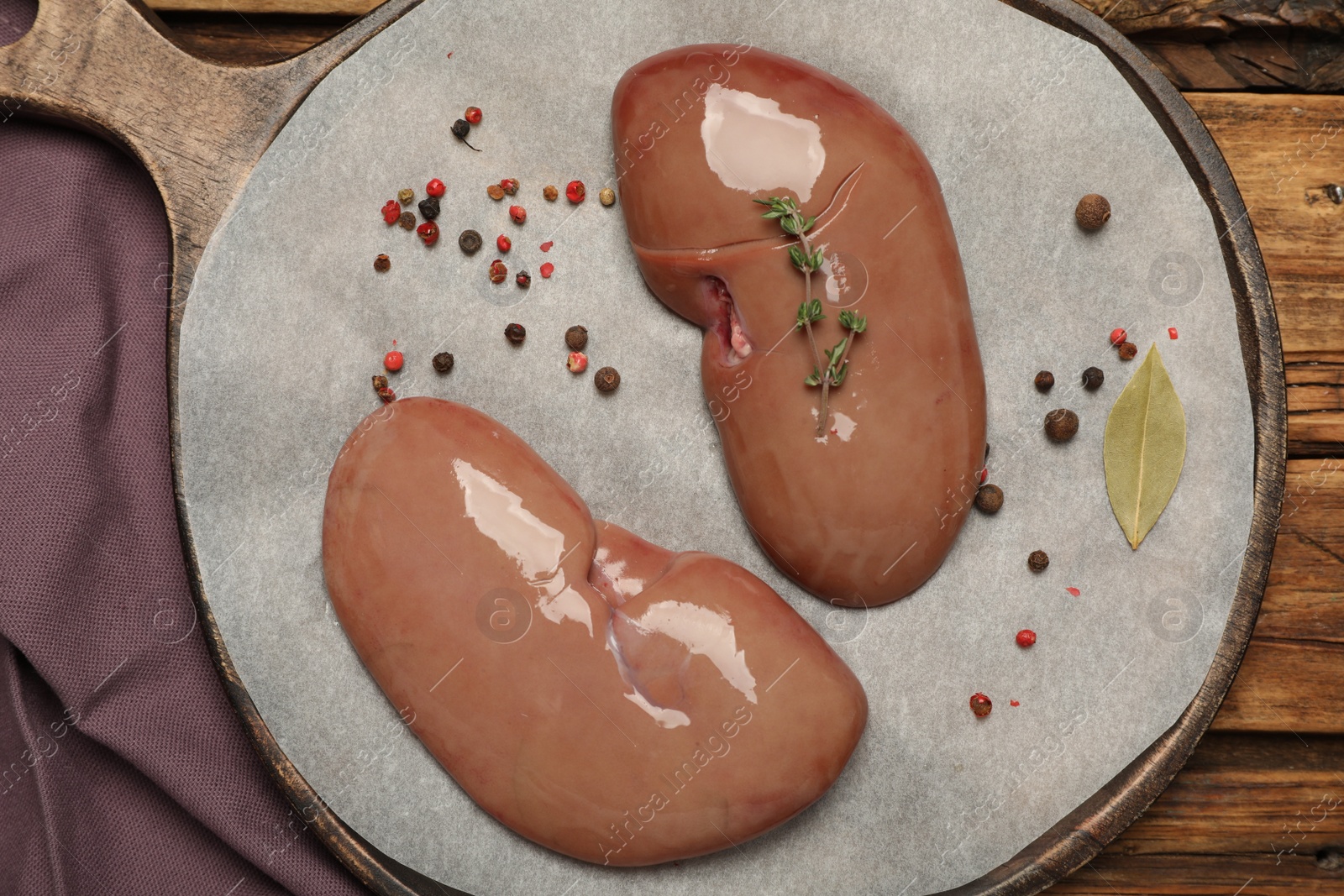 Photo of Fresh raw pork kidneys on wooden table, flat lay