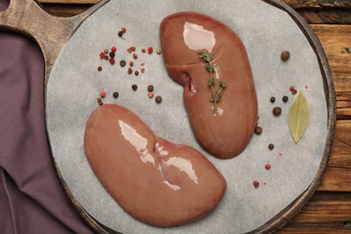 Photo of Fresh raw pork kidneys on wooden table, flat lay