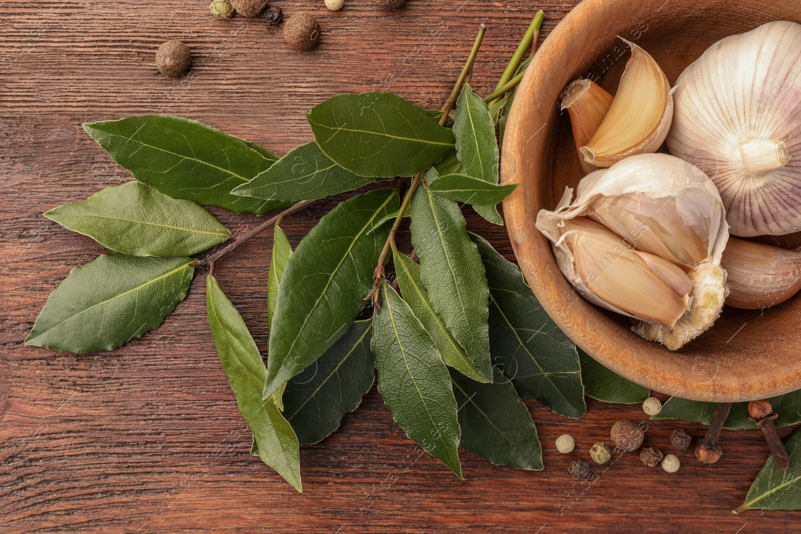 Photo of Aromatic bay leaves and spices on wooden table, flat lay