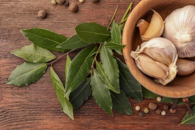 Aromatic bay leaves and spices on wooden table, flat lay
