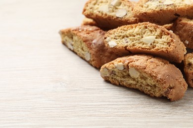 Photo of Traditional Italian almond biscuits (Cantucci) on white wooden table, closeup. Space for text