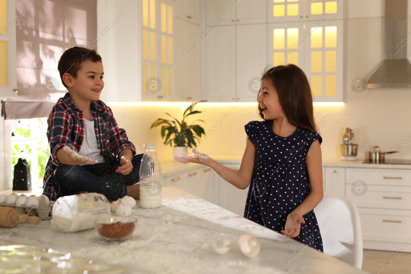 Photo of Cute little children cooking dough in kitchen at home