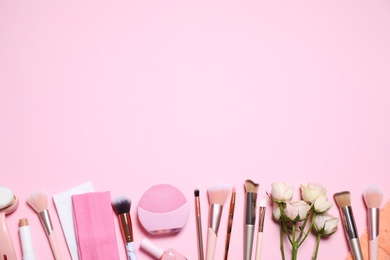 Photo of Different makeup brushes, accessories and flowers on pink background, flat lay. Space for text