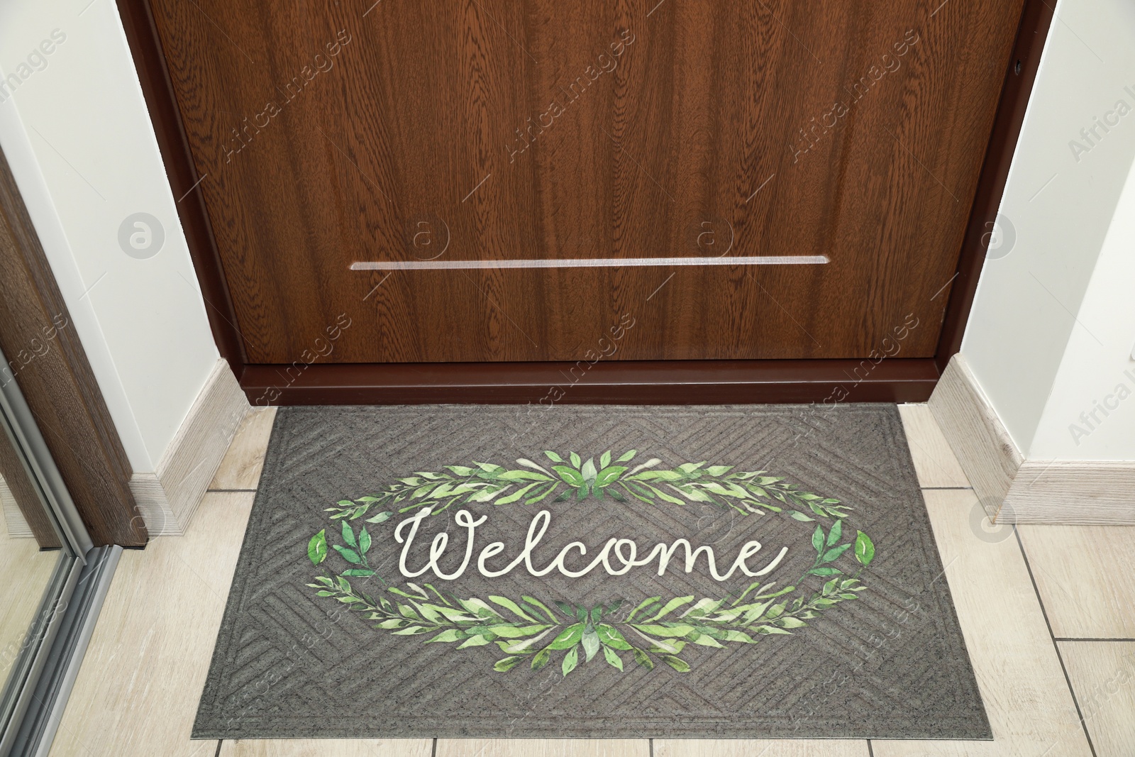 Photo of Beautiful doormat with word Welcome on floor near entrance