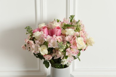Photo of Beautiful bouquet of fresh flowers in vase near white wall