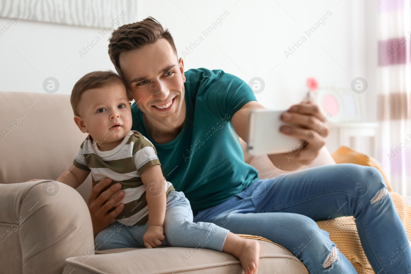 Photo of Young father with his cute little son taking selfie at home