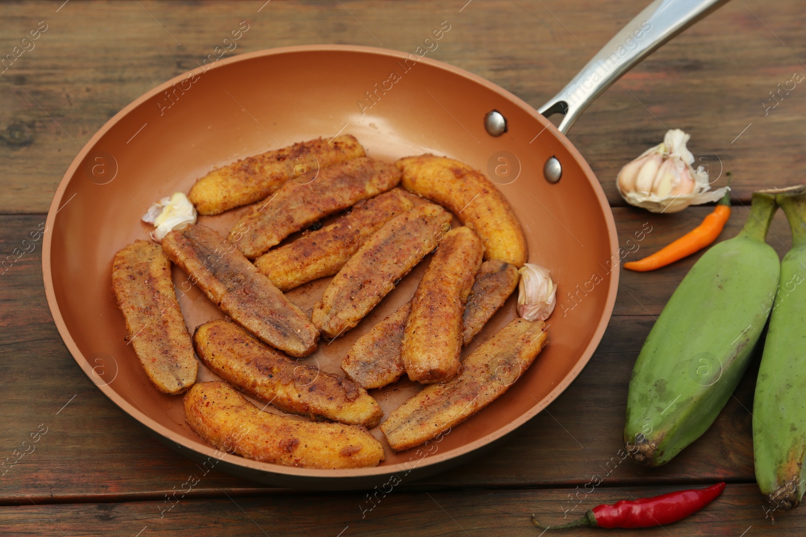 Photo of Delicious fried bananas, fresh fruits and different peppers on wooden table