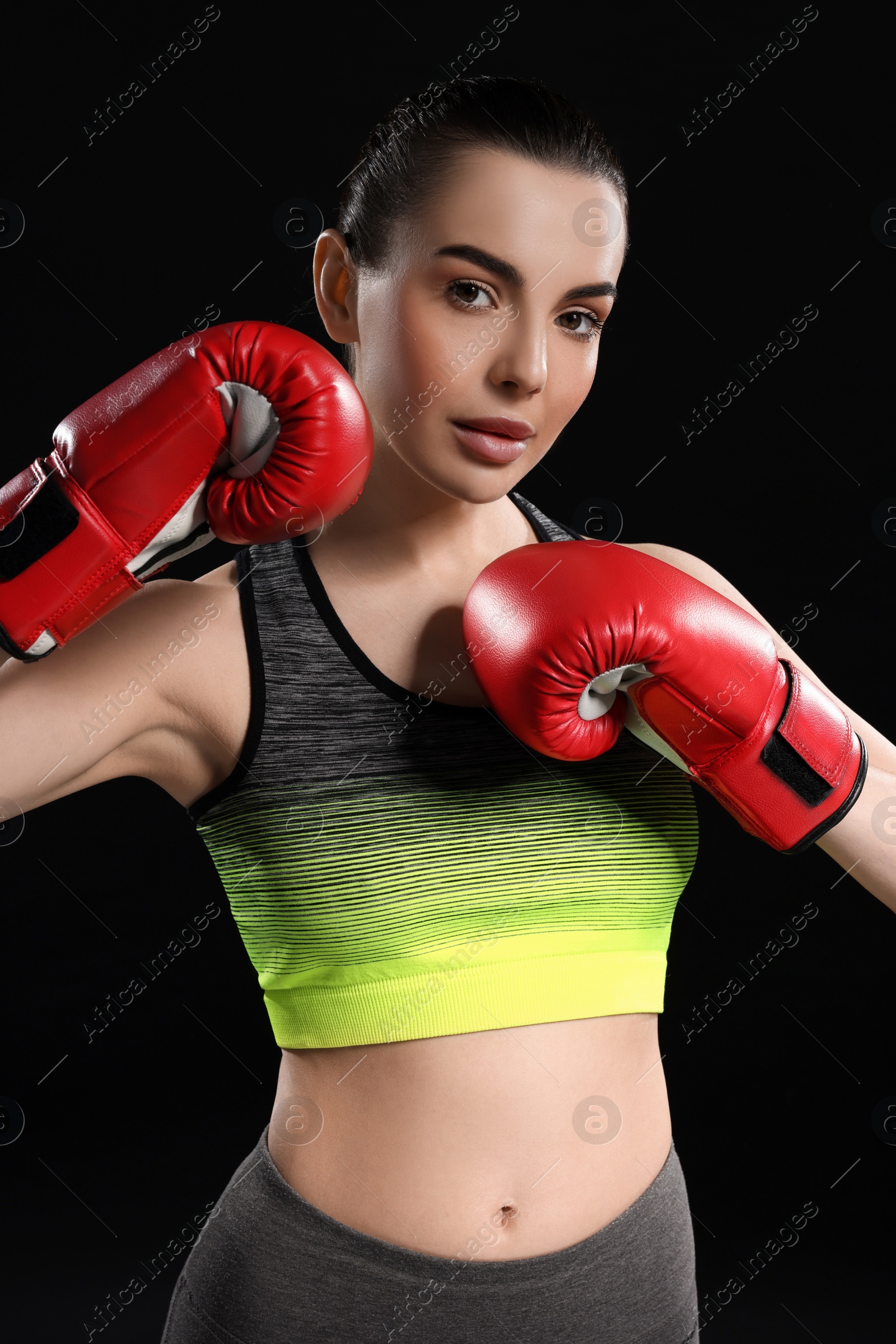 Photo of Portrait of beautiful woman in boxing gloves on black background