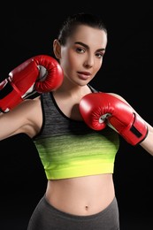 Portrait of beautiful woman in boxing gloves on black background