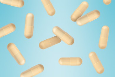 Image of Vitamin. Capsules falling on light blue gradient background