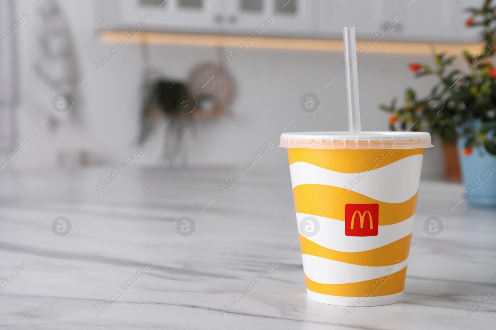 Photo of MYKOLAIV, UKRAINE - AUGUST 12, 2021: Cold McDonald's drink on marble table in kitchen. Space for text