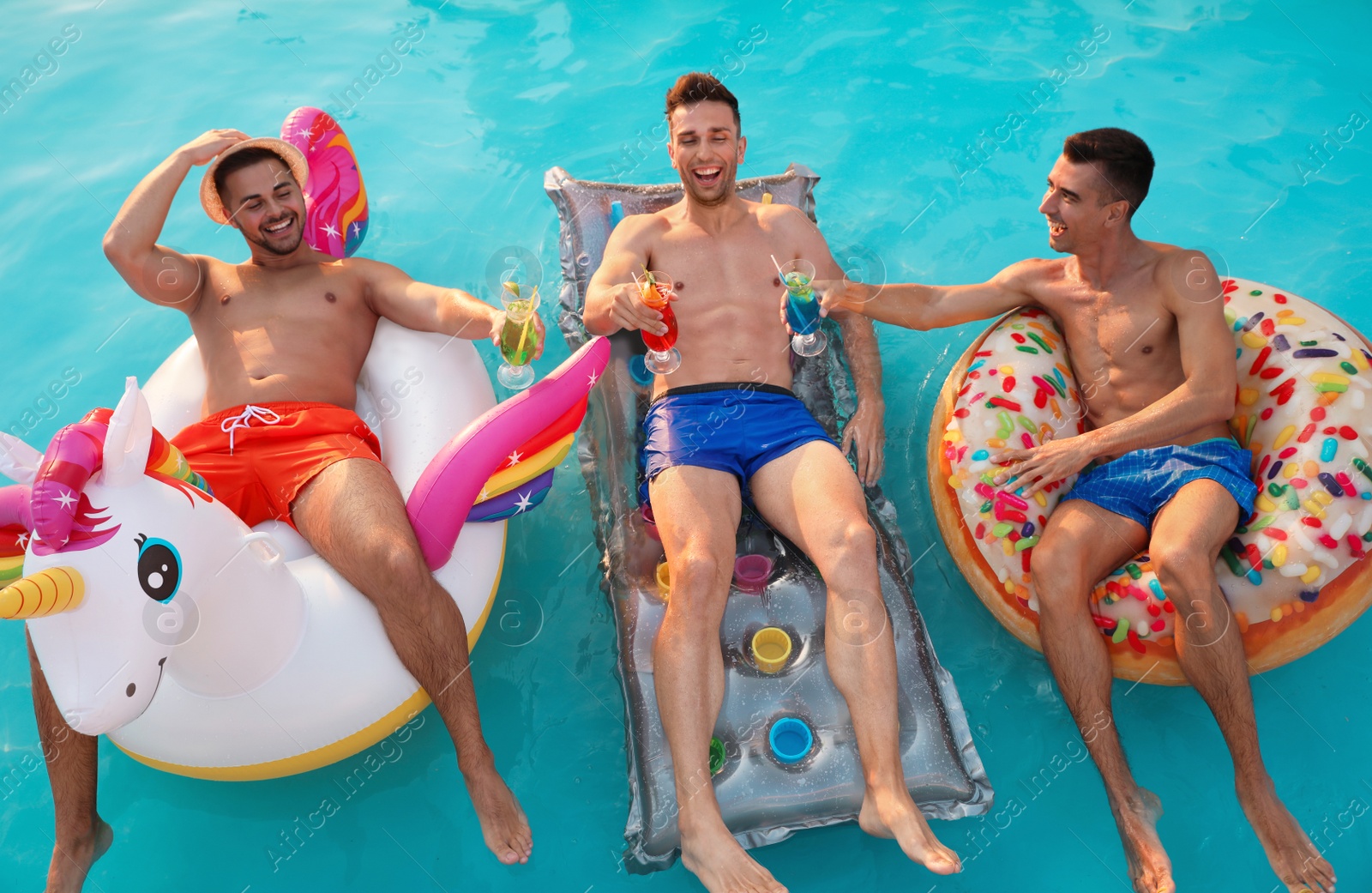 Photo of Happy young friends with refreshing cocktails relaxing in swimming pool