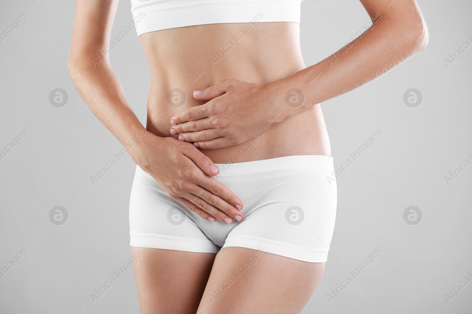 Photo of Young woman holding hands near panties on grey background. Gynecology concept