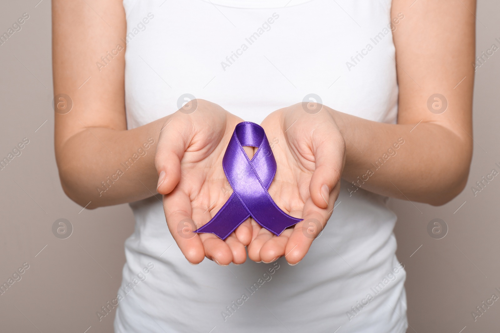 Photo of Woman holding purple ribbon on grey background, closeup. Domestic violence awareness