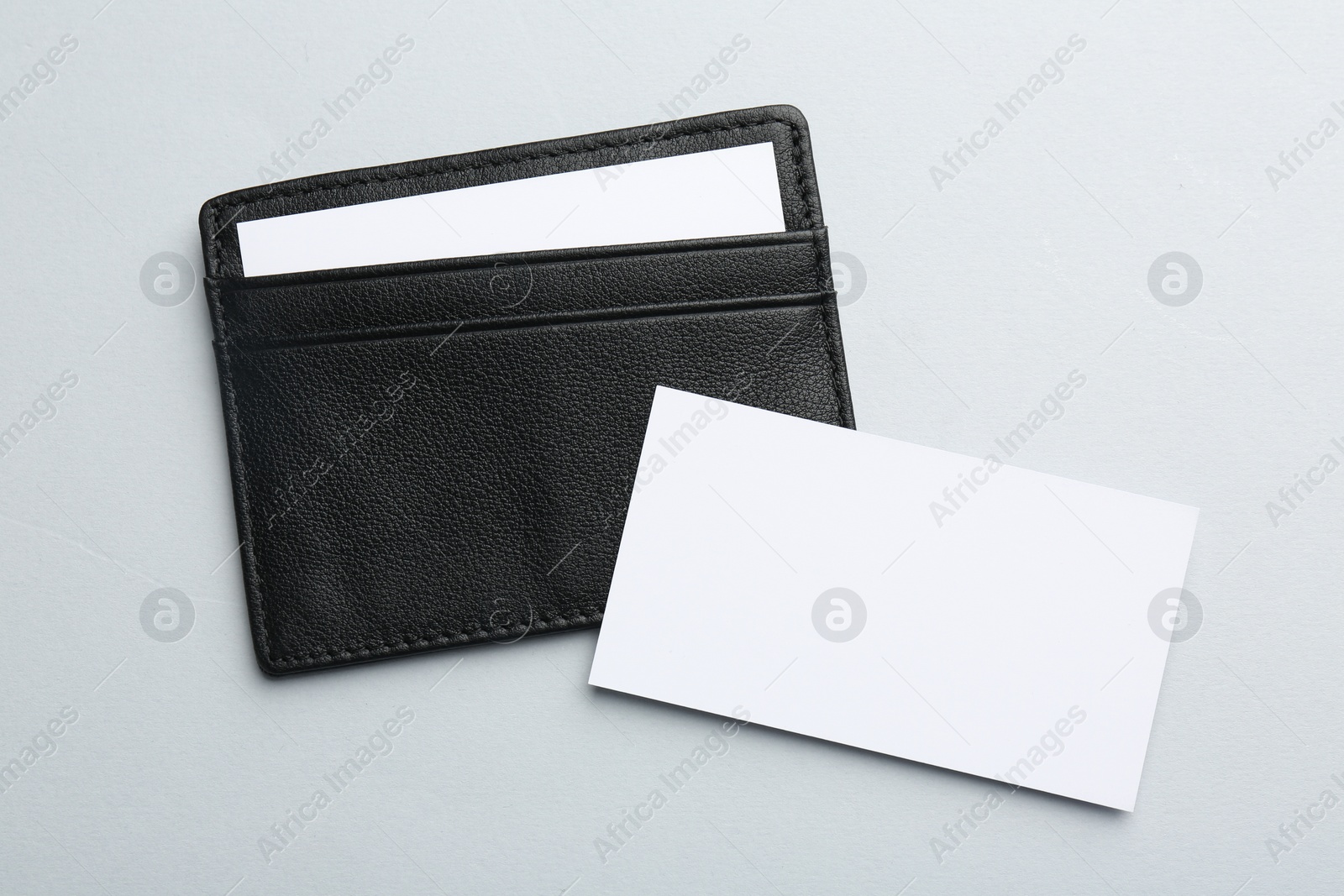 Photo of Leather business card holder with blank cards on light grey background, top view