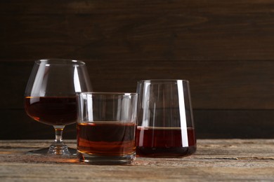 Photo of Different delicious liqueurs in glasses on wooden table