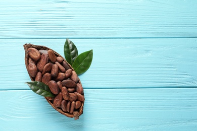 Half of cocoa pod with beans on blue wooden table, top view. Space for text