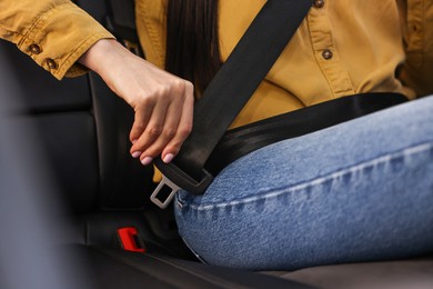 Photo of Woman fastening safety seat belt inside modern car, closeup