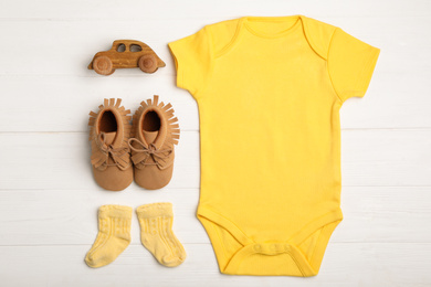 Photo of Flat lay composition with child's clothes and booties on white wooden table