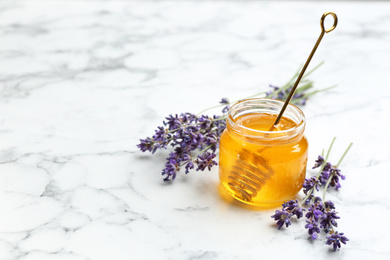 Photo of Tasty honey and lavender flowers on white marble table. Space for text
