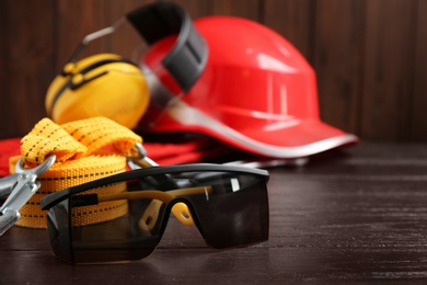 Photo of Black goggles and blurred safety equipment on background. Space for text
