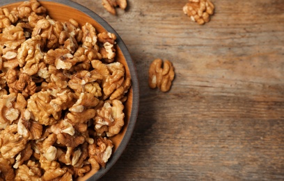 Plate with walnuts and space for text on wooden background, top view