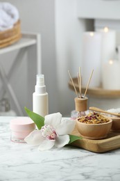 Beautiful composition with different spa products and orchid flower on white marble table indoors