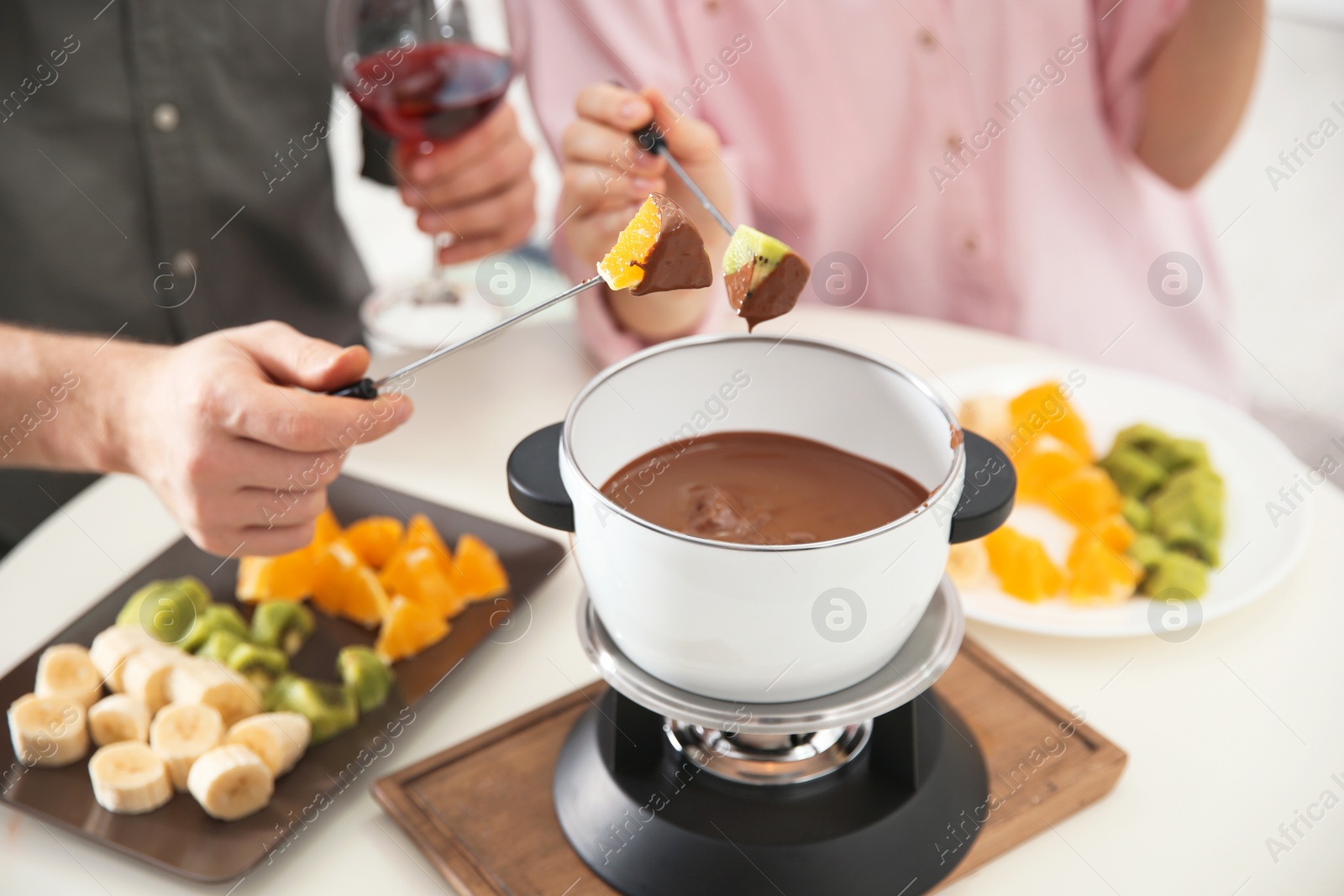 Photo of Couple having fondue dinner at table, closeup