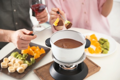 Photo of Couple having fondue dinner at table, closeup