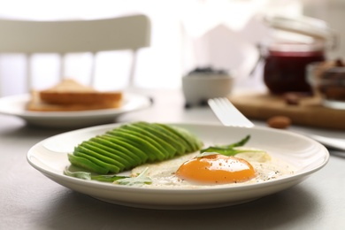 Tasty breakfast with fried egg and avocado on table