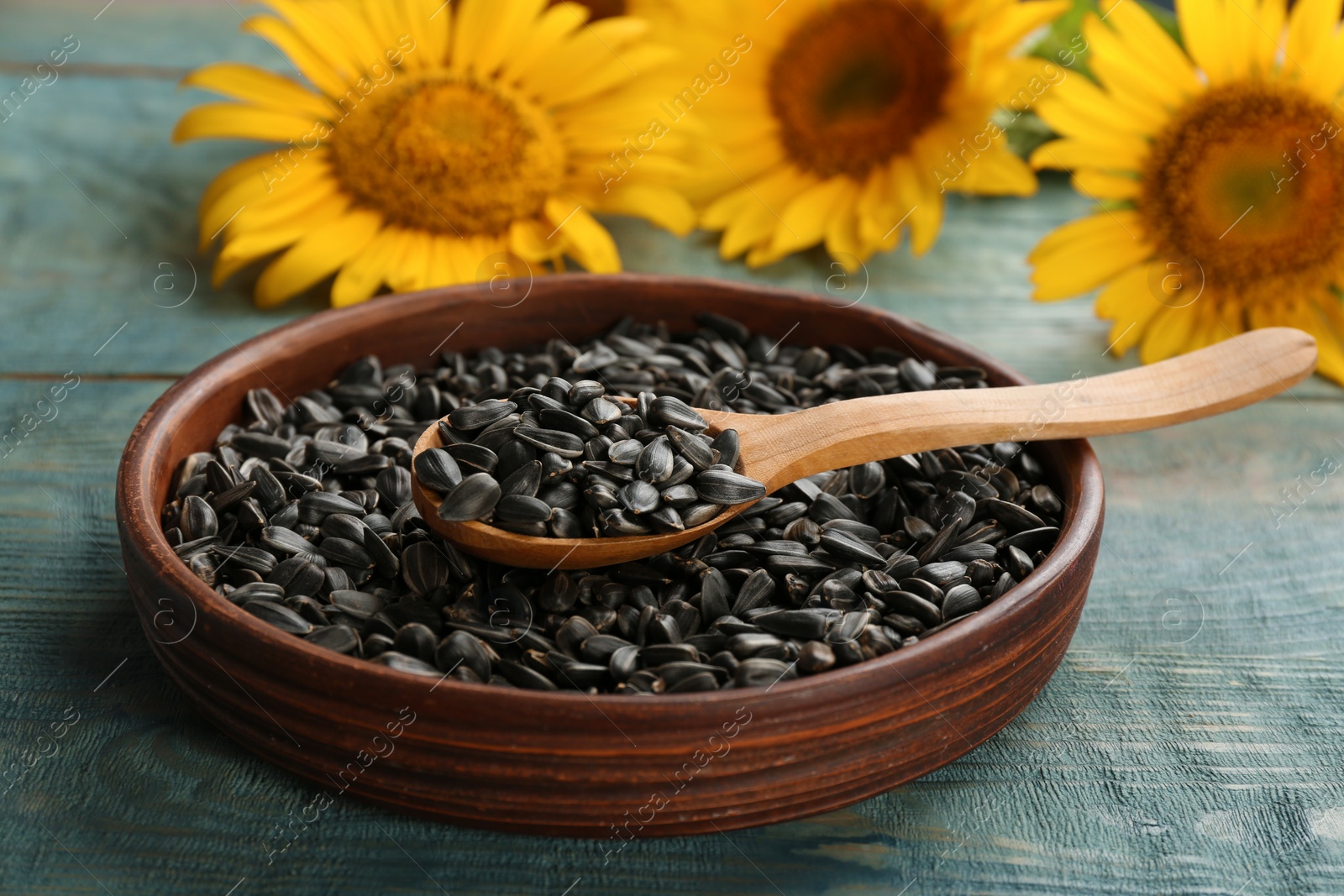 Photo of Bowl and spoon with sunflower seeds on table, closeup